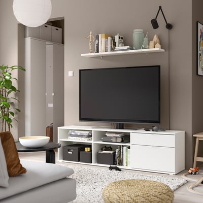 Moderní obývací pokoj s bílou TV stolkou VIHALS, TV s plochou obrazovkou, bílou pohovkou a minimalistickým zařízením.