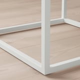 Tento obrázek ukazuje detailní záběr na moderní bílou kovovou polici s hladkými hranami a čistými liniemi, která zdůrazňuje její robustní a moderní design.