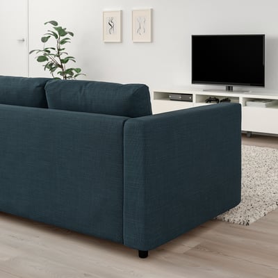 Moderní obývací pokoj s modrou sekční pohovka VIMLE, TV, umění, rostlina, dřevěné podlahy, koberec.