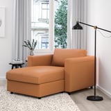 Moderní obývací pokoj s velkou oranžovou třímístnou pohovkou VIMLE, vedle ní černá stojací lampa.