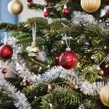 Vánoční stromeček zdobený červenými a zlatými plastovými ozdobami VINTERFINT, mezi stříbrnými pozlátky, různé velikosti a tvaru.