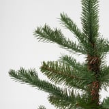 Detailní záběr na umělou větev borovice, která ukazuje živé, hustě napěchované jehličí a silné hnědé stonky.