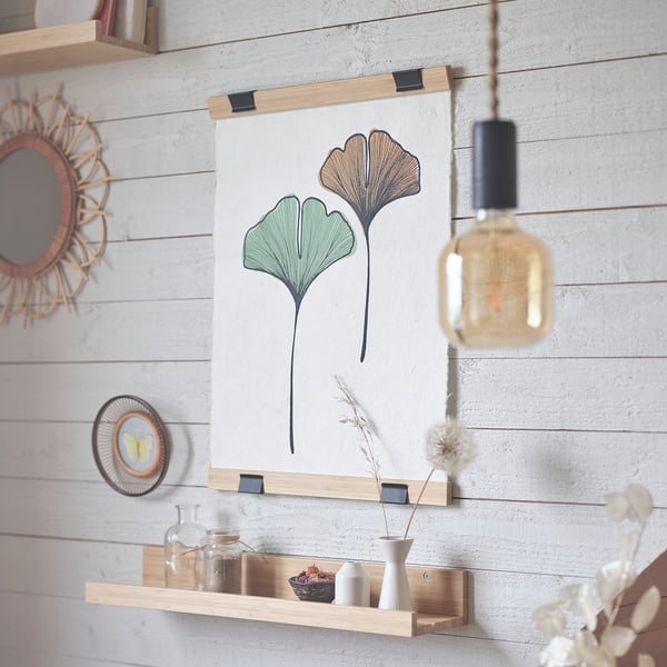Minimalistická ložnice s věšákem na plakáty VISBÄCK, žárovkou a vázami.