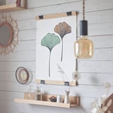 Minimalistická ložnice s věšákem na plakáty VISBÄCK, žárovkou a vázami.