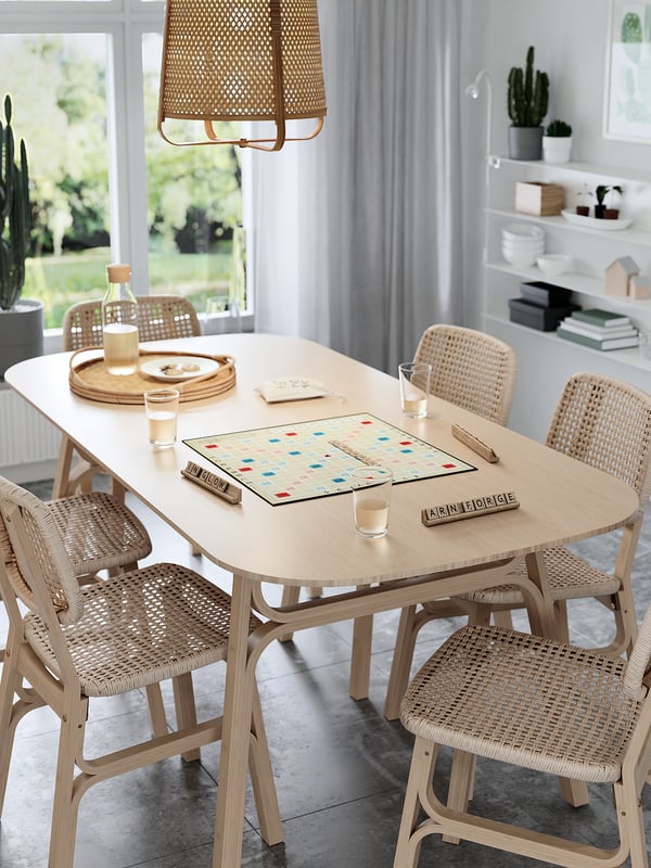 Moderní jídelní set se scrabble boardem, světlé dřevo, proutěné židle, přirozené světlo.