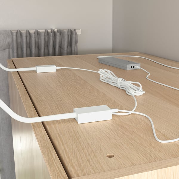 Dřevěný povrch s tenkými, flexibilními LED světelnými pásy, ovládanými na dálku, osvětlujícími prostor.