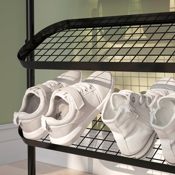 Black metal shoe rack with white sneakers, tilting shelves for varied sizes.