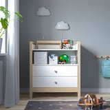 White nursery table with toys, lamps, and backpack.