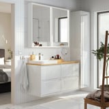 ÄNGSJÖN white bathroom vanity with wood countertop, two mirrors, sink, storage, towel, chair, plant.