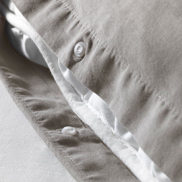 Close-up of white duvet cover with concealed press studs down the side, showing soft, washed cotton fabric.