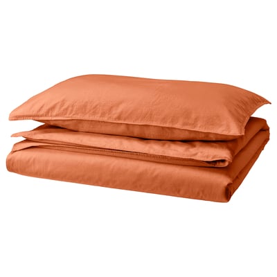 A neatly folded rust-colored bedding set named ÄNGSLILJA. It includes a duvet cover and pillowcases made from soft, recycled cotton.