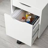 White rolling drawer unit with colorful containers, holding office supplies. Great for organizing and moving around.