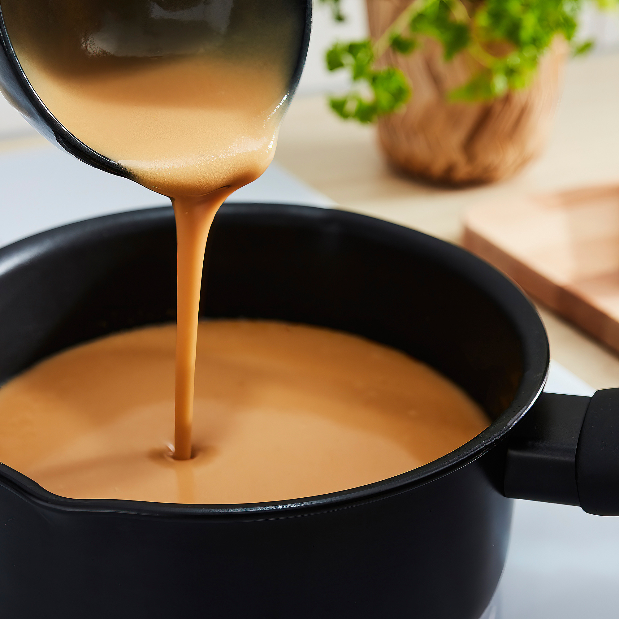 Pouring sauce into black pan with herbs.