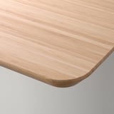 Light wood desk corner close-up, smooth surface and rounded edges.