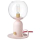 The ÅSKMULLER lamp is a sleek, modern table lamp in a light pink color with a rounded glass shade and gold accents, giving off a warm, cozy light.