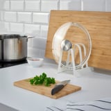 Modern kitchen organizer with lids & boards near stove.