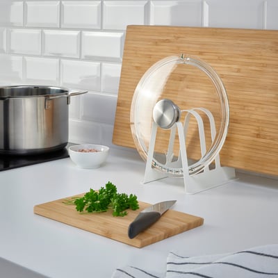 Modern kitchen organizer with lids & boards near stove.