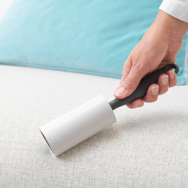 Hand holds BÄSTIS lint roller on fabric.