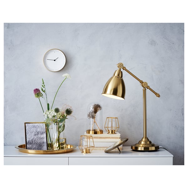 A golden desk lamp and a glass dome display on a shelf.