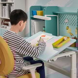 Child drawing at adjustable BERGLÄRKA desk with storage.