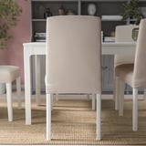 Beige dining chairs with white legs around white table on rug. Covers are removable.