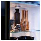 Glass shelves in cabinet displaying vases and bowls, demonstrating airy organization.