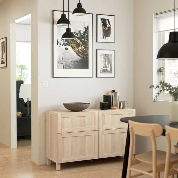 Modern kitchen with wooden sideboard featuring drawers & adjustable shelves, against wall with art and lights.