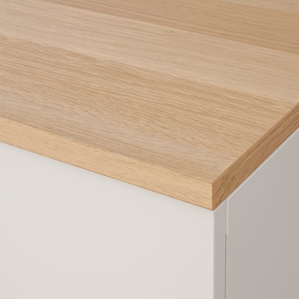 Close-up of a sturdy, light-hued wooden tabletop on a white cabinet, showcasing smooth finish and quality craftsmanship.