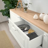White sideboard with utensils, cutting boards, vases, and plants.