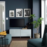 Modern living room with BESTÅ tv stand, tv, & decor. Blue walls, teal furniture.