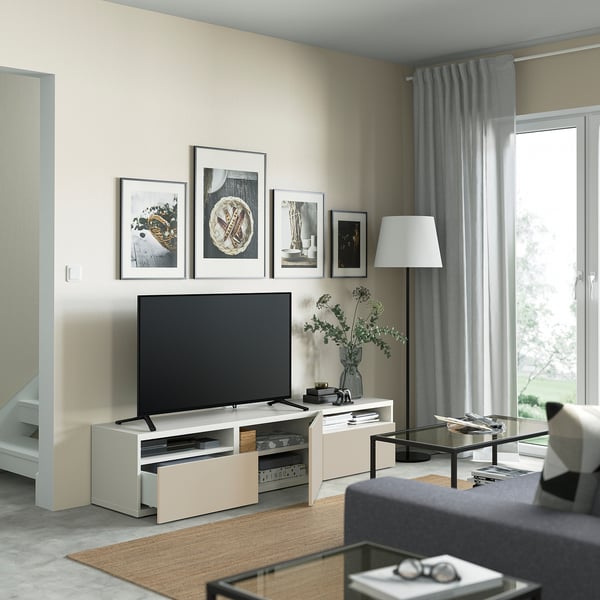 Modern living room with BESTÅ tv stand, flat-screen tv, art, lamp, and coffee table with flowers.
