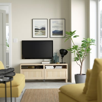 Modern living room with BESTÅ tv unit, yellow chairs, wall art, plant, and lamp.