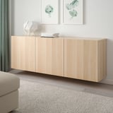BESTÅ storage unit with doors in room, neutral wood, rug, sofa.