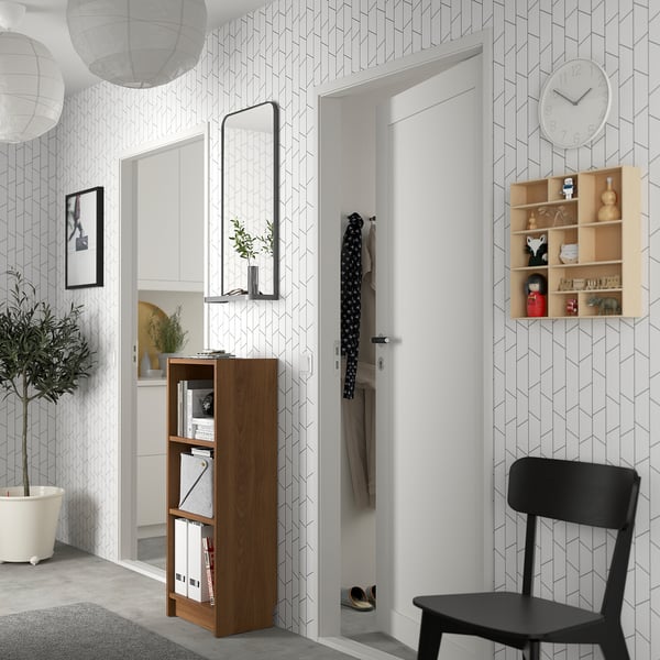 Modern entryway with BILLY bookcase, greenery, chair, & geometric wall.