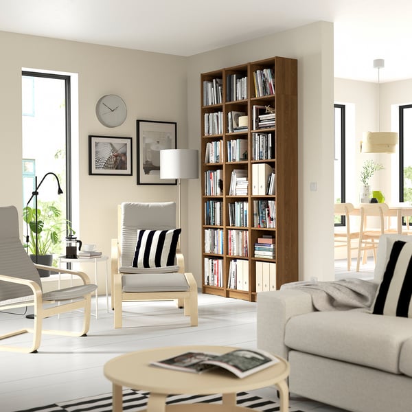 Modern living room with BILLY bookcase, gray sofa, armchairs, and natural light.
