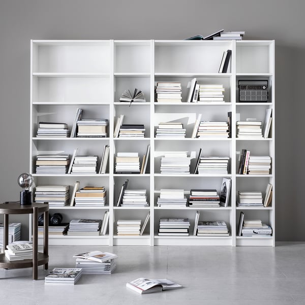 Large white BILLY bookcases with numerous books and minimalist decor. Clean, organized, modern design.
