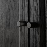 Close-up of black wooden texture with two cylindrical knobs, showcasing BILLYs quality craftsmanship.