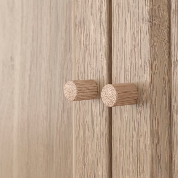 Wooden cabinet with two cylindrical knobs; smooth finish, natural texture.