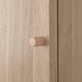 Close-up view of light wooden cabinet with cylindrical handle.