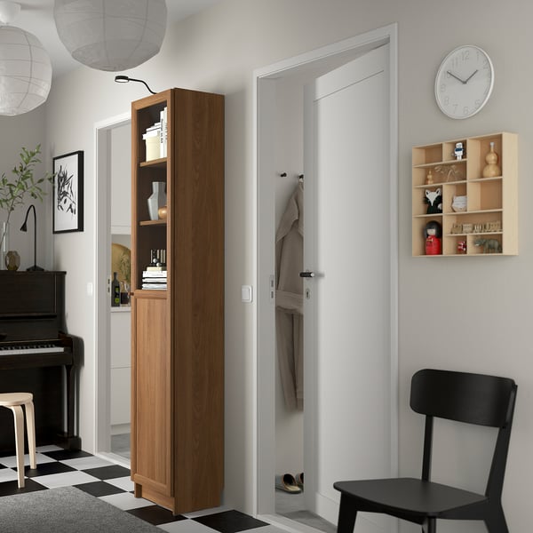 Tall BILLY bookcase with glass doors, chair, and white door.
