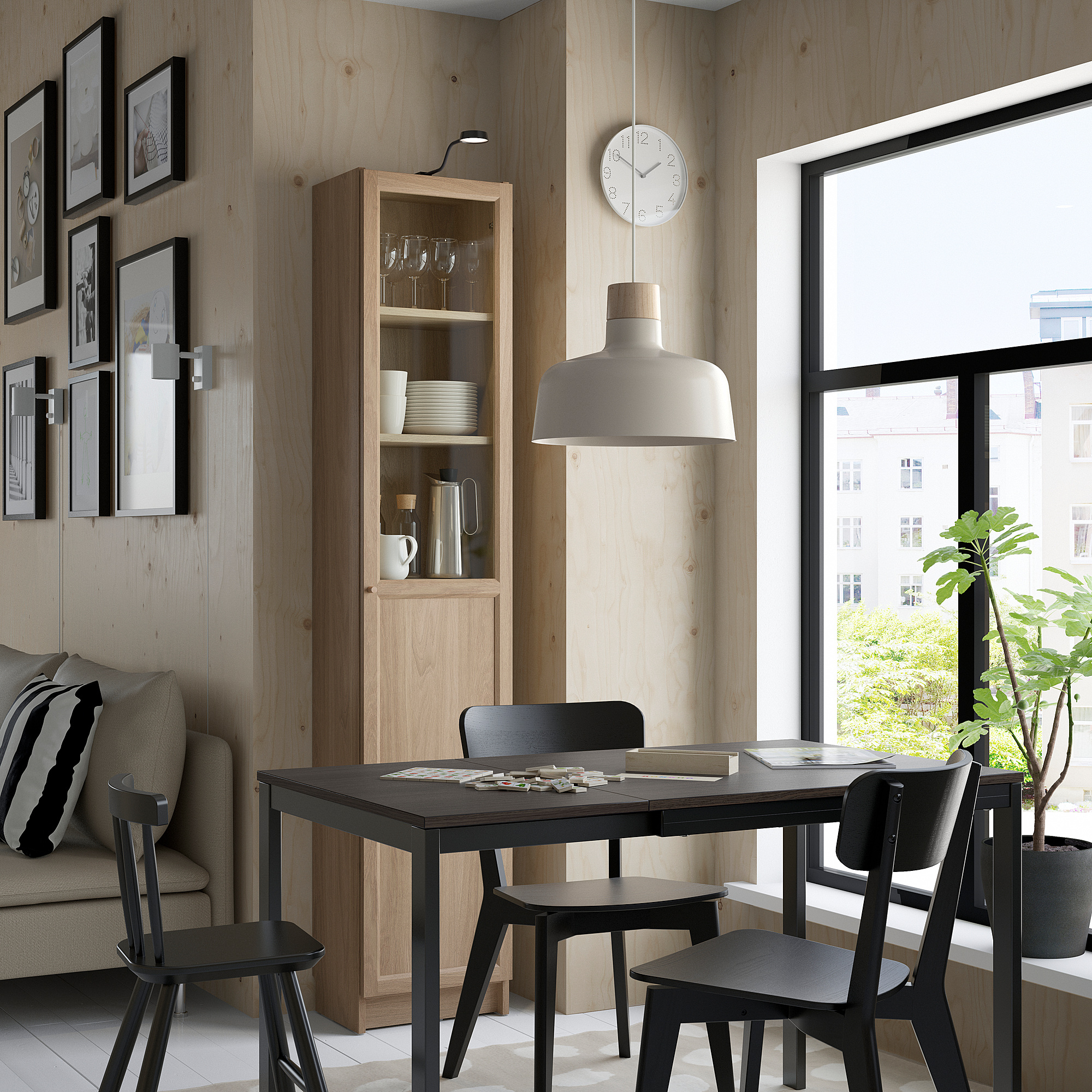 Modern dining area with black table, BILLY bookcase, pendant light, cozy sofa, and window view of greenery.