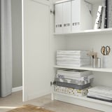 White bookshelf with adjustable shelves, holding storage boxes, games, and office supplies. One door open, revealing organized items.