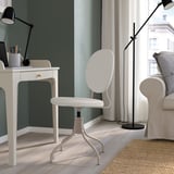Modern home office with white BJÖRKBERGET chair. Sleek design, padded, adjustable. Desk, lamp, and sofa nearby. Large window with view.