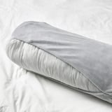 A soft, cylindrical cushion on a bed. Its versatile for supporting various body parts, perfect for kids from age 3.