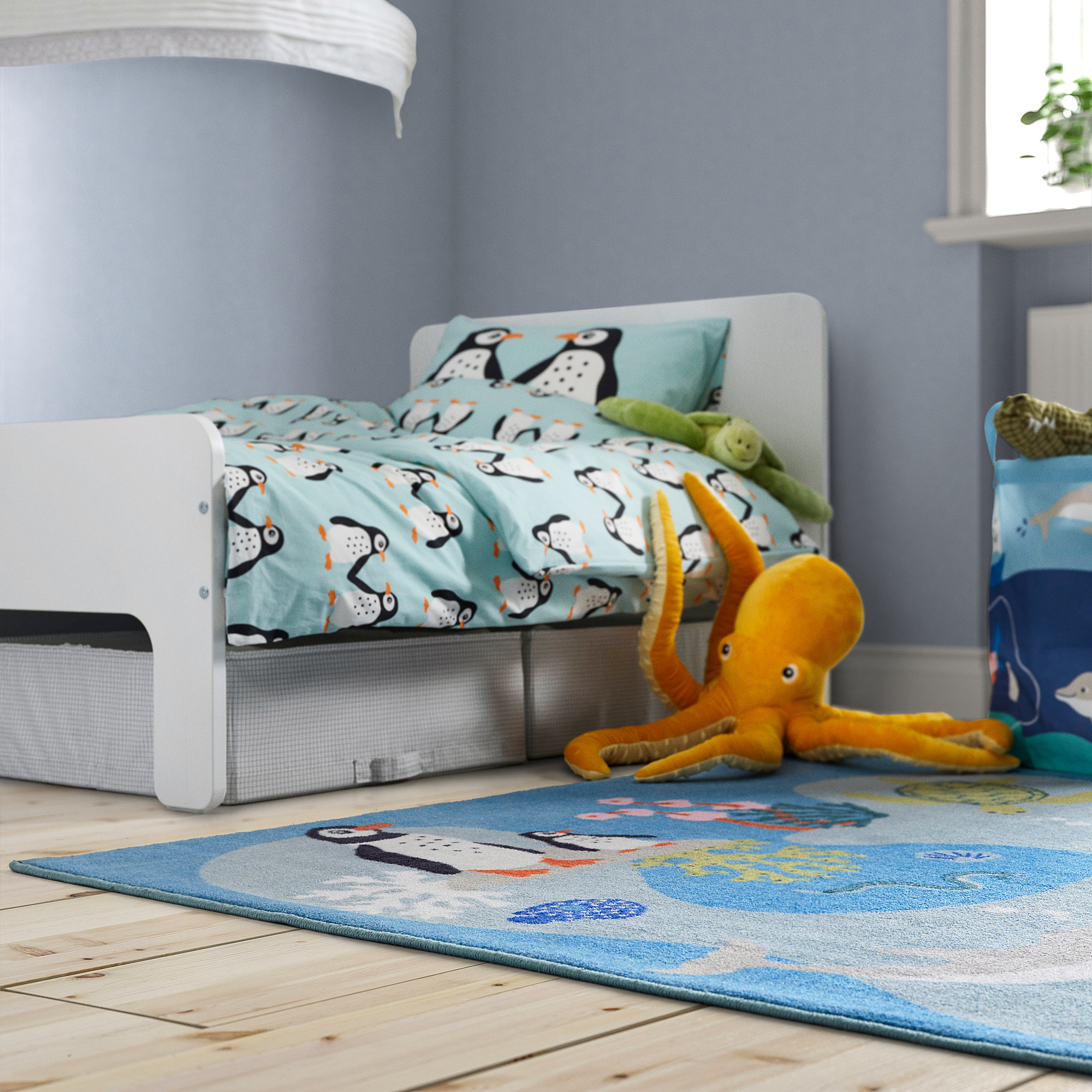 Kids blue ocean-themed rug, white floor, small bed. Soft, recycled materials, fits room size.