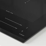 Black induction hob with beveled edge, five cooking zones, touch controls, and boost functions.