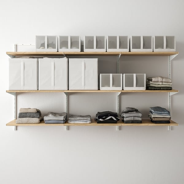 Wall-mounted storage system with shelves and boxes. Clothes neatly folded and stacked on shelves. Clear boxes on top shelf, holding various items.