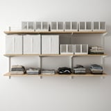 Wall-mounted storage system with shelves and boxes. Clothes neatly folded and stacked on shelves. Clear boxes on top shelf, holding various items.