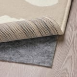 A rolled rug with a non-slip underlay on a wooden floor.