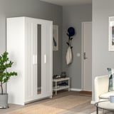 Modern white BRIMNES wardrobe with mirror door beside entrance, sleek design.